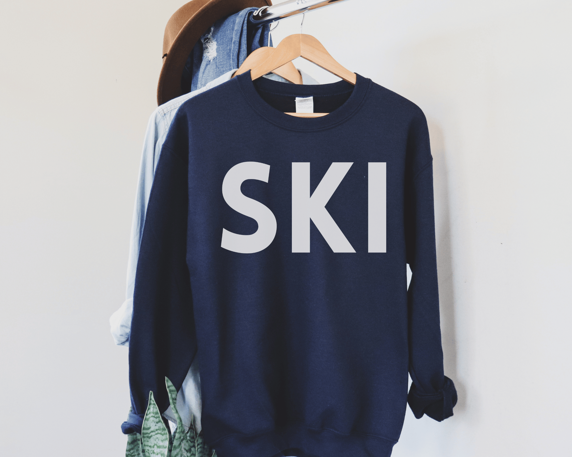 Ski Sweatshirt in Navy, hanging on a hanger.